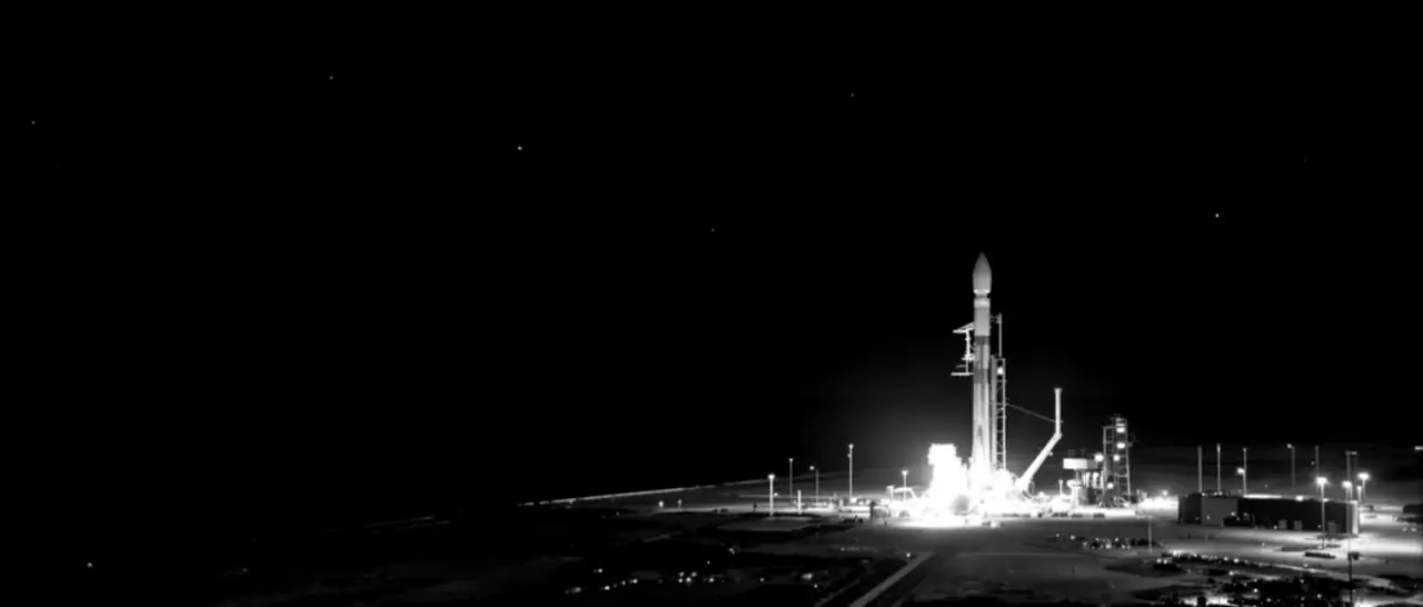 A rocket climbing into the night sky, its exhaust trail arcing up from the launch site